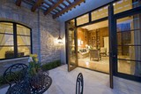 Photo: House exterior at night with some patio furniture and open patio doors looking into the lit interior House exterior at night with some patio furniture and open patio doors looking into the lit interior