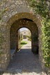 Outside archway with an open gate revealing part of a house in the distant