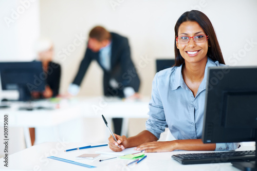 Photo: Smiling young business woman at office desk Smiling young business woman at office desk