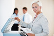 Confident young woman photocopying at the office