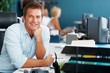 Happy businessman sitting at desk in office