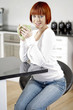 Young female enjoying a hot drink in her kitchen