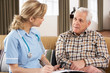 Senior Man Talking To Health Visitor At Home