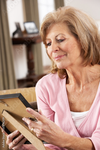 Photo: Senior Woman Looking At Photograph In Frame Senior Woman Looking At Photograph In Frame