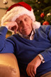 Tired Senior Man Relaxing In Front Of Christmas Tree