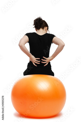 Photo: junge frau mit rückenschmerzen sitzt auf einem gymnastikball junge frau mit rückenschmerzen sitzt auf einem gymnastikball