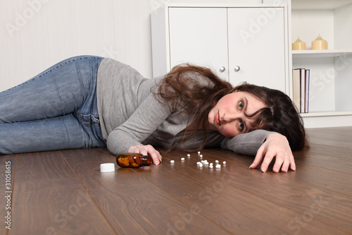 Photo: Depressed teenage girl lying on floor with pills Depressed teenage girl lying on floor with pills