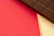 Stick of white and dark chocolate on a red background