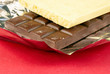 Stick of white and dark dessert chocolate on a red background