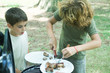Photo: Boy cutting up meat on plate while second boy watches Boy cutting up meat on plate while second boy watches
