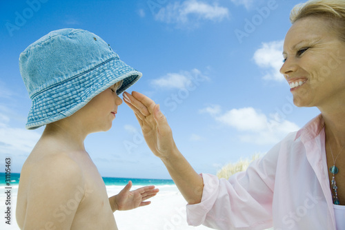 Photo: Mother putting sunscreen on child at beach Mother putting sunscreen on child at beach