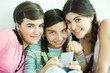 Three young female friends holding make-up, smiling at camera
