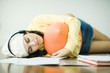 Young woman lying on floor listening to headphones, neglecting homework
