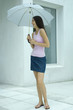 Woman standing under umbrella, full length portrait
