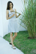 Woman looking at ornamental plant, holding stems, full length