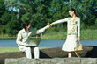 Photo: Man sitting on tree trunk with laptop on lap, reaching for woman's hand as she approaches Man sitting on tree trunk with laptop on lap, reaching for woman's hand as she approaches