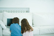 Boy and girl using laptop on sofa, rear view