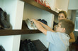 Boy putting shoes on shoe rack while mother watches