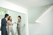 Female real estate agent showing house to young couple, pointing to blueprints
