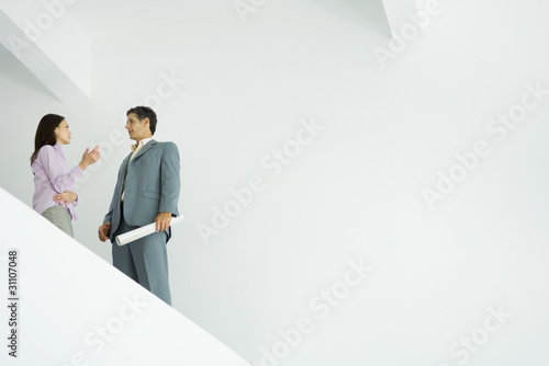 Photo: Young woman standing speaking with architect, low angle view Young woman standing speaking with architect, low angle view