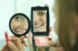 Photo: Two young friends putting on lipstick, looking at selves in hand mirrors, cropped view Two young friends putting on lipstick, looking at selves in hand mirrors, cropped view