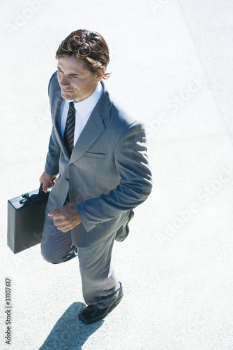 Photo: Young businessman walking outdoors, carrying briefcase, high angle view Young businessman walking outdoors, carrying briefcase, high angle view