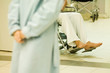 Patient sitting in wheel chair, cropped view, adult with clasped hands in foreground