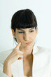 Photo: Young businesswoman puffing cheeks out, holding finger to cheek, looking away, portrait Young businesswoman puffing cheeks out, holding finger to cheek, looking away, portrait