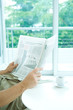 Photo: Man reading newspaper at table, cropped view Man reading newspaper at table, cropped view