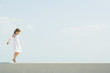 Little girl walking across low wall, arms out, looking down