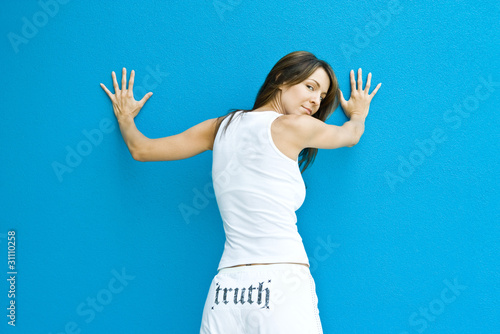 Photo: Woman in pants with the word truth" on backside, standing with hands against wall, looking over shoulder at camera" Woman in pants with the word truth" on backside, standing with hands against wall, looking over shoulder at camera"