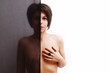 Naked woman standing behind a veil, covering her breast Naked woman standing behind a veil, covering her breast