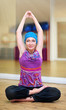Young woman doing yoga on the floor of gym