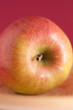 Roter Apfel mit rotem Hintergrund auf Holzteller Roter Apfel mit rotem Hintergrund auf Holzteller