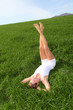 Woman laying down green field with legs up