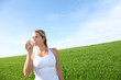 Woman drinking natural water in green field