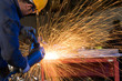 Sparks made by factory worker using electric grinder.