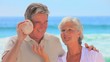 Mature couple listening to shell together