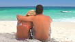Couple sitting on the sand looking at the sea