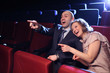 Photo: Young couple in cinema movie theater laughing at comedy Young couple in cinema movie theater laughing at comedy