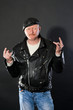 Middle-aged male dressed in leather posing as biker in studio