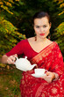 woman in Indian sari with teapot and cup of tea