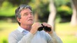 Mature man watching something through binoculars