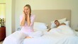 Young woman with a headache while husband sleeps