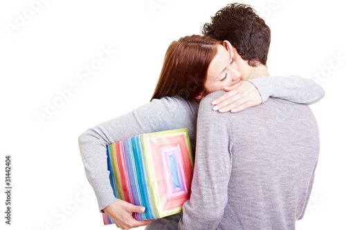 Foto: Frau mit Geschenk umarmt Mann Frau mit Geschenk umarmt Mann