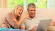 Attractive couple looking and laughing at laptop