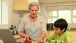 Little boy cooking with his grandmother