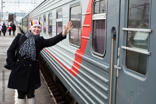 Photo: Girl says goodbye departing train and waves by hand after him Girl says goodbye departing train and waves by hand after him