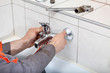 Plumbers hands fixing water tap in a bathroom Plumbers hands fixing water tap in a bathroom