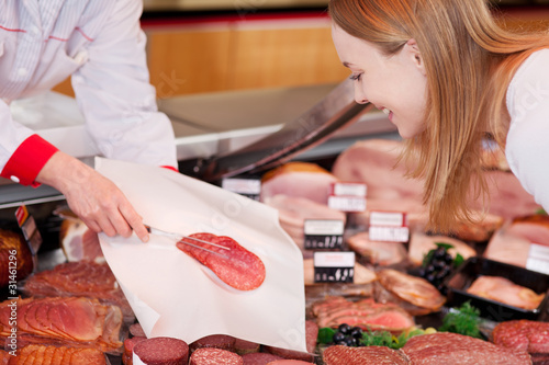 Foto: verkäuferin zeigt scheiben salami verkäuferin zeigt scheiben salami